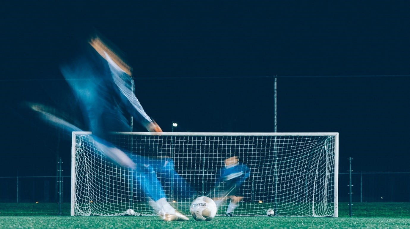 Men playing football hitting a goal